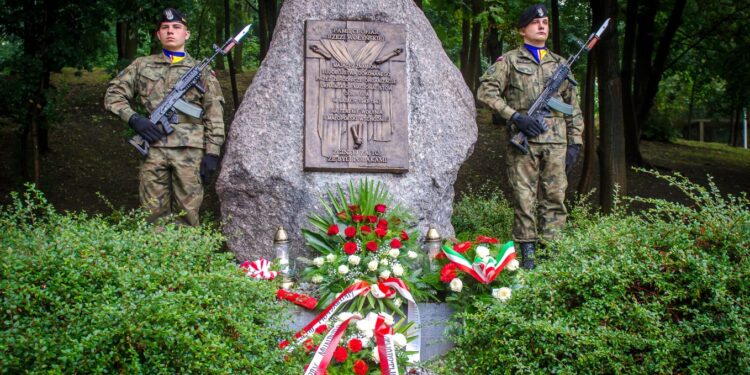 Kwiaty pod tablicą poświęconą pamięci ofiar Zbrodni Wołyńskiej